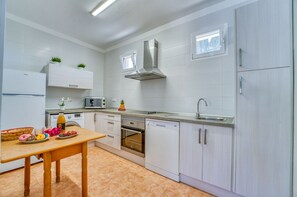 A modern kitchen with white cabinetry, a stainless steel range hood, a built-in oven, and a dishwasher. - Finca with pool Son Manyo 2 Petit in Sa Pobla (Sa Pobla)