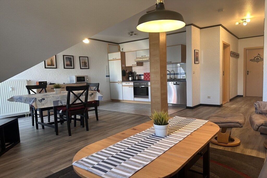 Eine moderne Küche mit Essbereich, einer Treppe zu einer oberen Ebene und einer gemütlichen Sitzecke mit Sofa und Hocker.