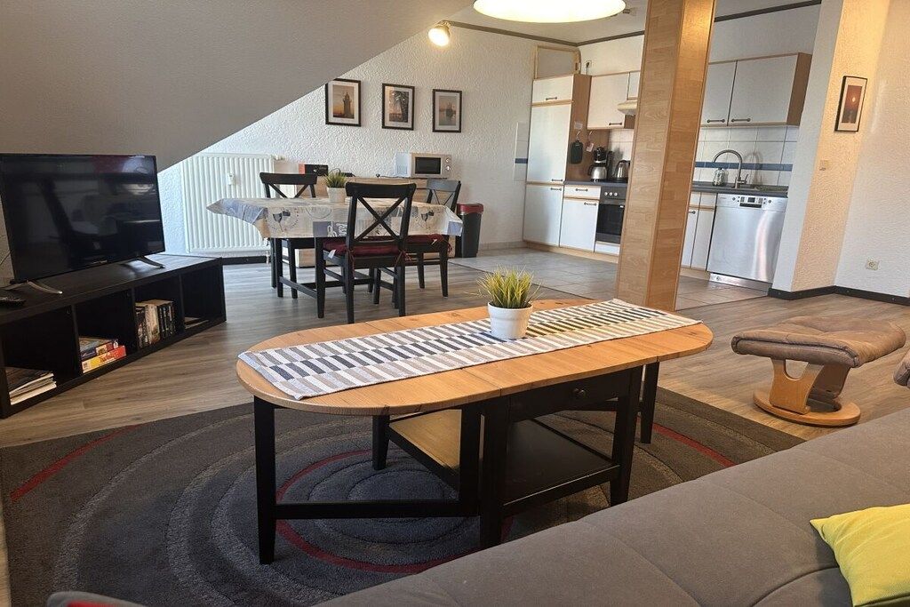 A modern living room with a television, a dining table, and a sofa.