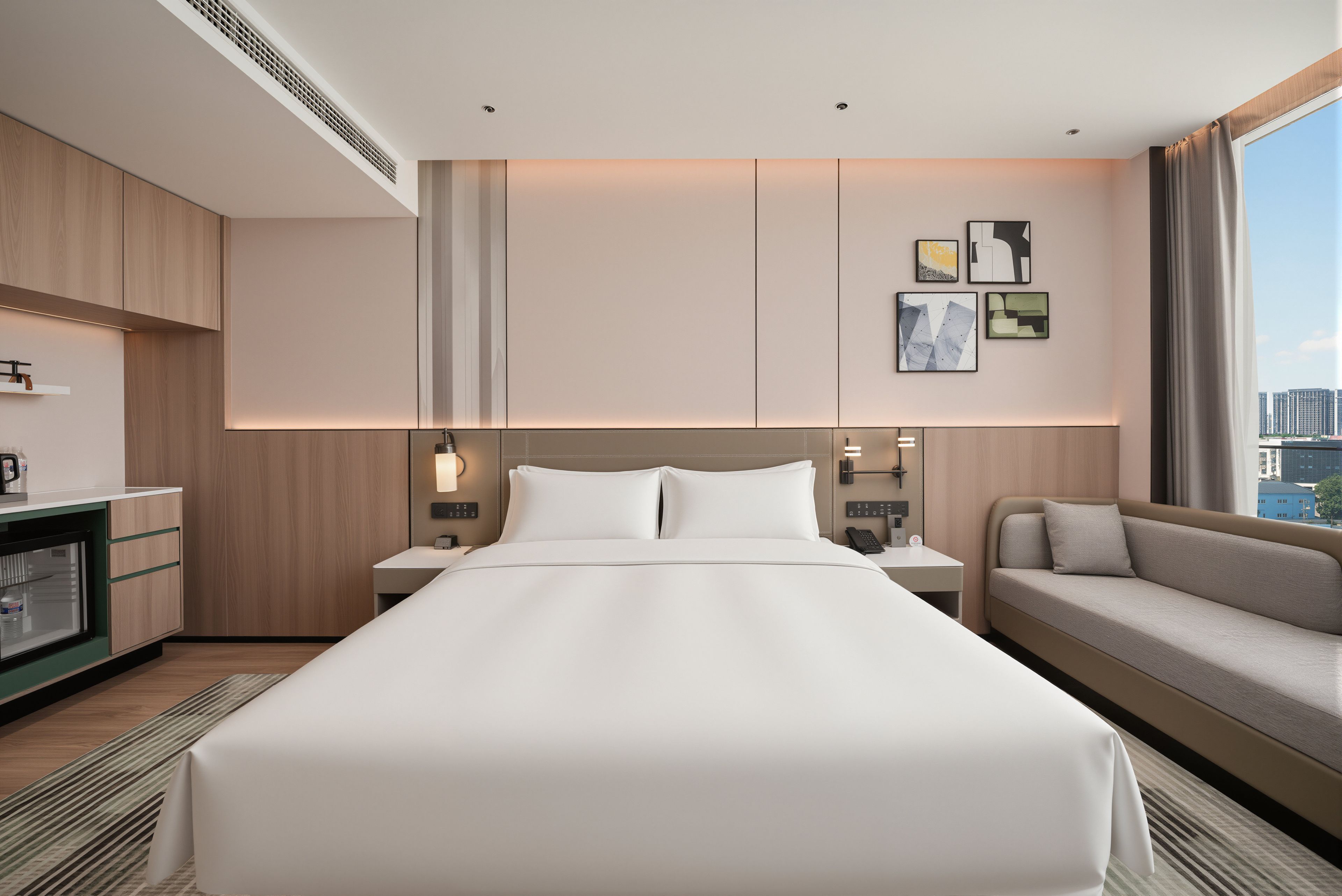 Ein Hotelzimmer mit einem großen Bett, einer Couch, einem Schreibtisch mit Lampe und Bildern an der Wand.