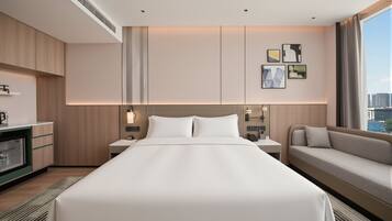 Ein Hotelzimmer mit einem großen Bett, einer Couch, einem Schreibtisch mit Lampe und Bildern an der Wand.