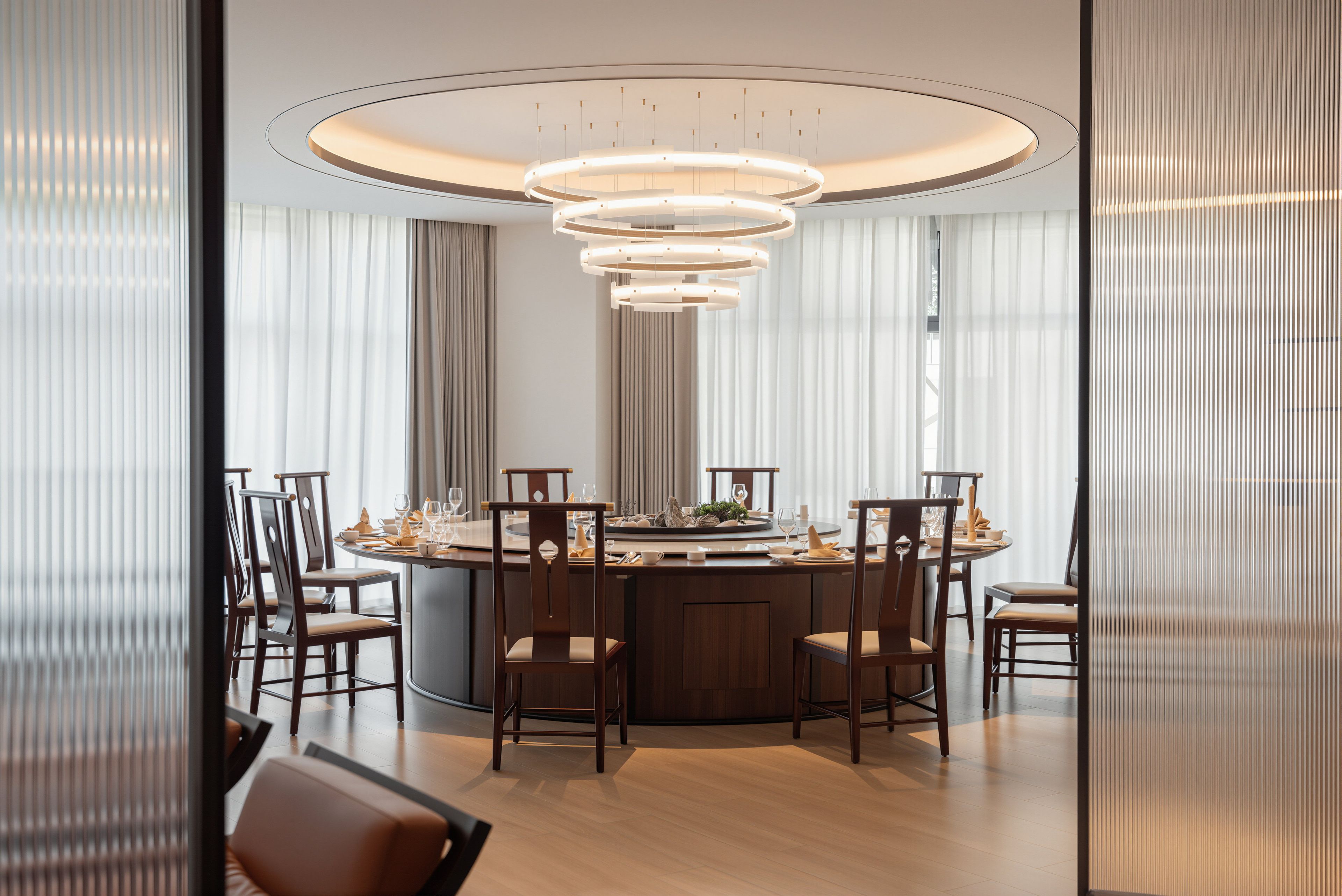 Un comedor moderno con una mesa redonda, sillas de madera y una lámpara de techo circular original.
