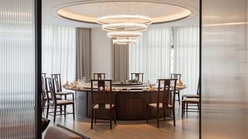 Un comedor moderno con una mesa redonda, sillas de madera y una lámpara de techo circular original.