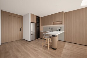 A modern kitchen with a built-in island, wooden cabinetry, and a stainless steel refrigerator.