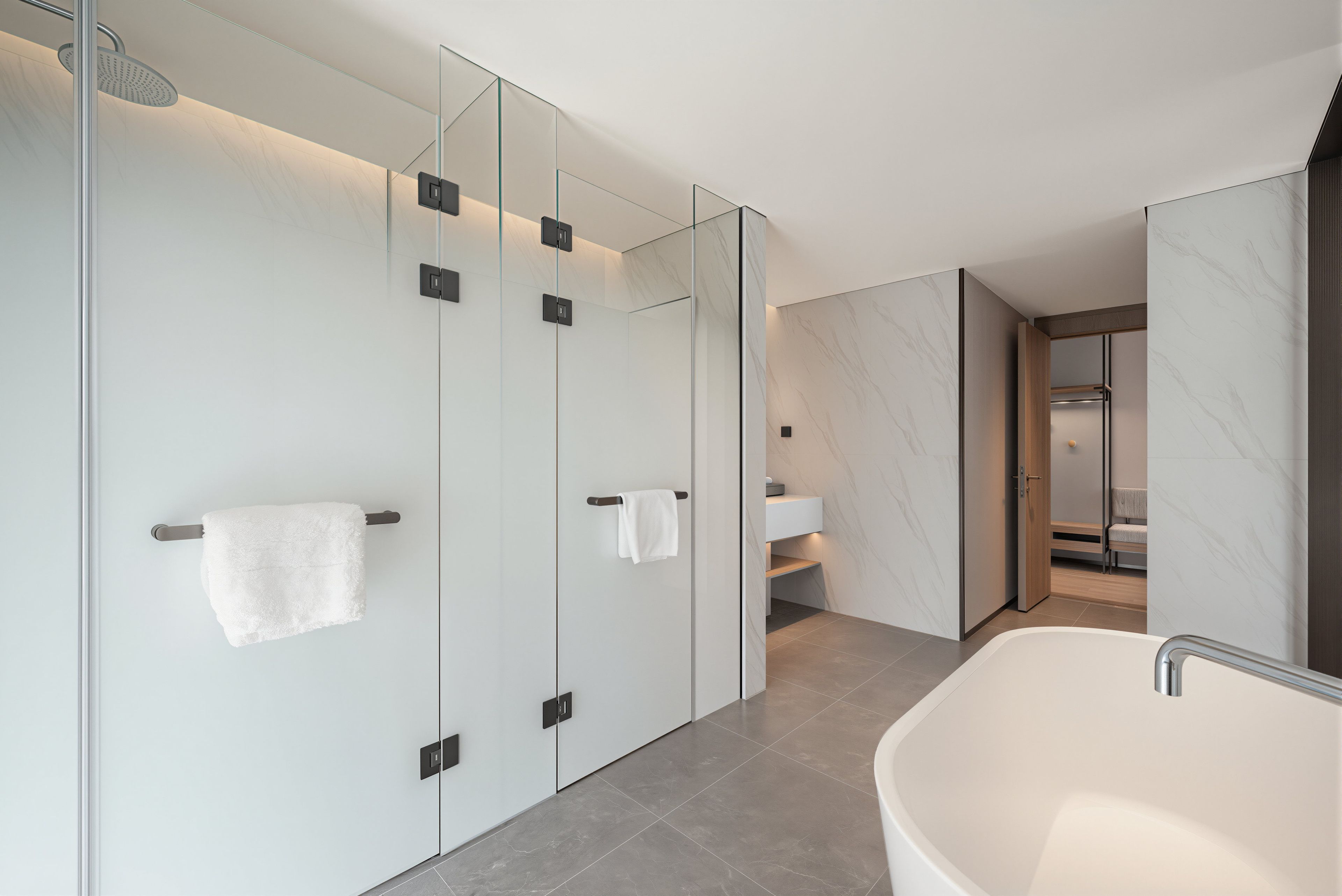 Ein modernes Badezimmer mit freistehender Badewanne, gläsernen Duschkabinen und einem marmorverlegten Boden.