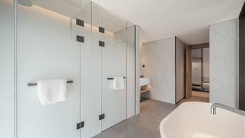 Ein modernes Badezimmer mit freistehender Badewanne, gläsernen Duschkabinen und einem marmorverlegten Boden.