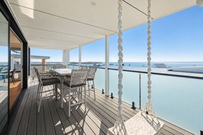 A wooden deck with a table and chairs, overlooking a body of water. - The Perch San Remo - an Incredible View by Ready Set Stay (San Remo)