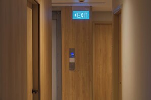 Un couloir avec une porte en bois et un panneau indiquant la sortie au-dessus.