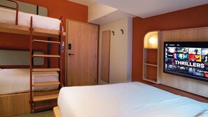 A hotel room with bunk beds, a wardrobe, a television displaying a movie selection, and a wall-mounted shelf. - ST Signature Midtown (Singapore)