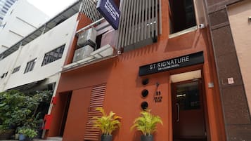 A hotel entrance with a sign reading 'St Signature Co-Living Hotel' and a number '85' indicating the address.