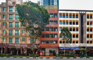 Un hôtel à plusieurs étages, reconnaissable à son grand panneau indiquant « PARK VIEW HOTEL », un bâtiment « ST SIGNATURE » et un bâtiment « CHIVE SING BUILDING » dont on peut voir l’escalier.