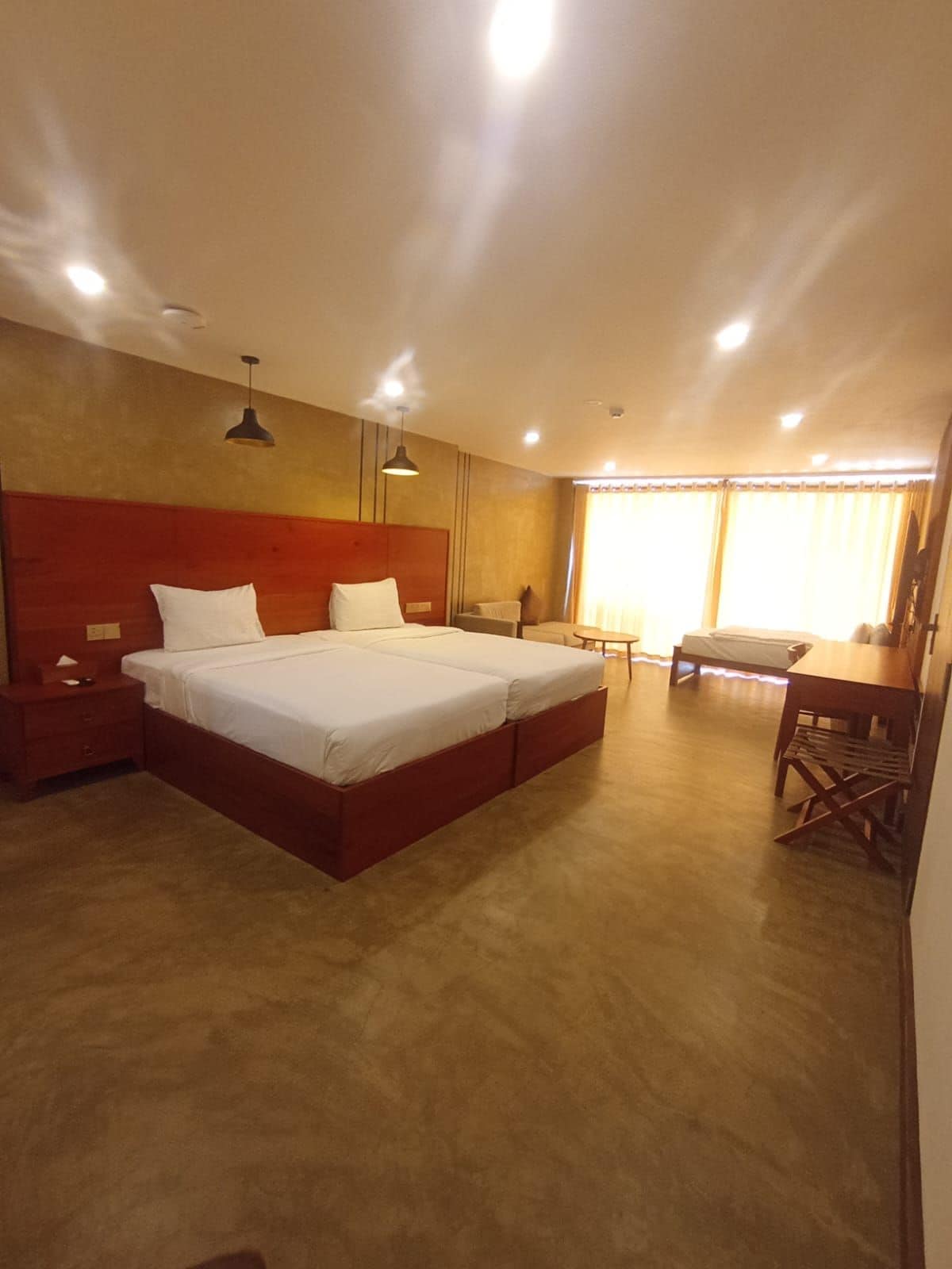 Ein Hotelzimmer mit einem großen Bett, Nachttischen, einem Schreibtisch und einem Stuhl.