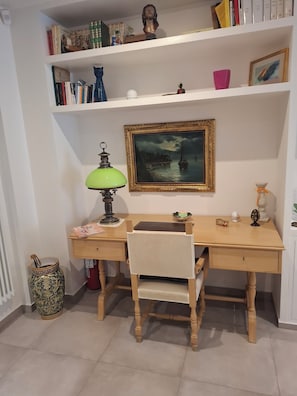 A study room with a desk, chair, bookshelf, lamp, and a framed painting. - The Perfect Home for Remote Work and Vacations: Living in Downtown Bari (Bari)