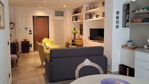 A modern living room with a sofa, dining table, and kitchen area in the background. - Vrbo Property (Bari)