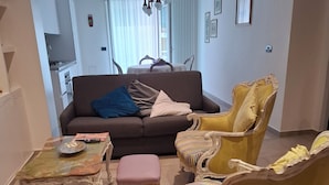 A living room with a sofa, armchairs, a coffee table, and a dining area in the background. - Vrbo Property (Bari)