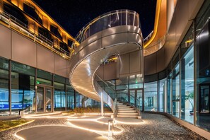 Un edificio moderno con escalera de caracol, ventanas de vidrio e iluminación exterior.