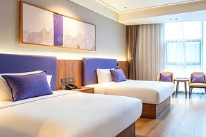 A hotel room with two beds, a desk, a chair, and a large window with curtains.