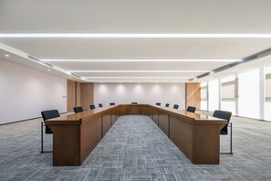 A conference room with a long table, chairs, and a carpeted floor.