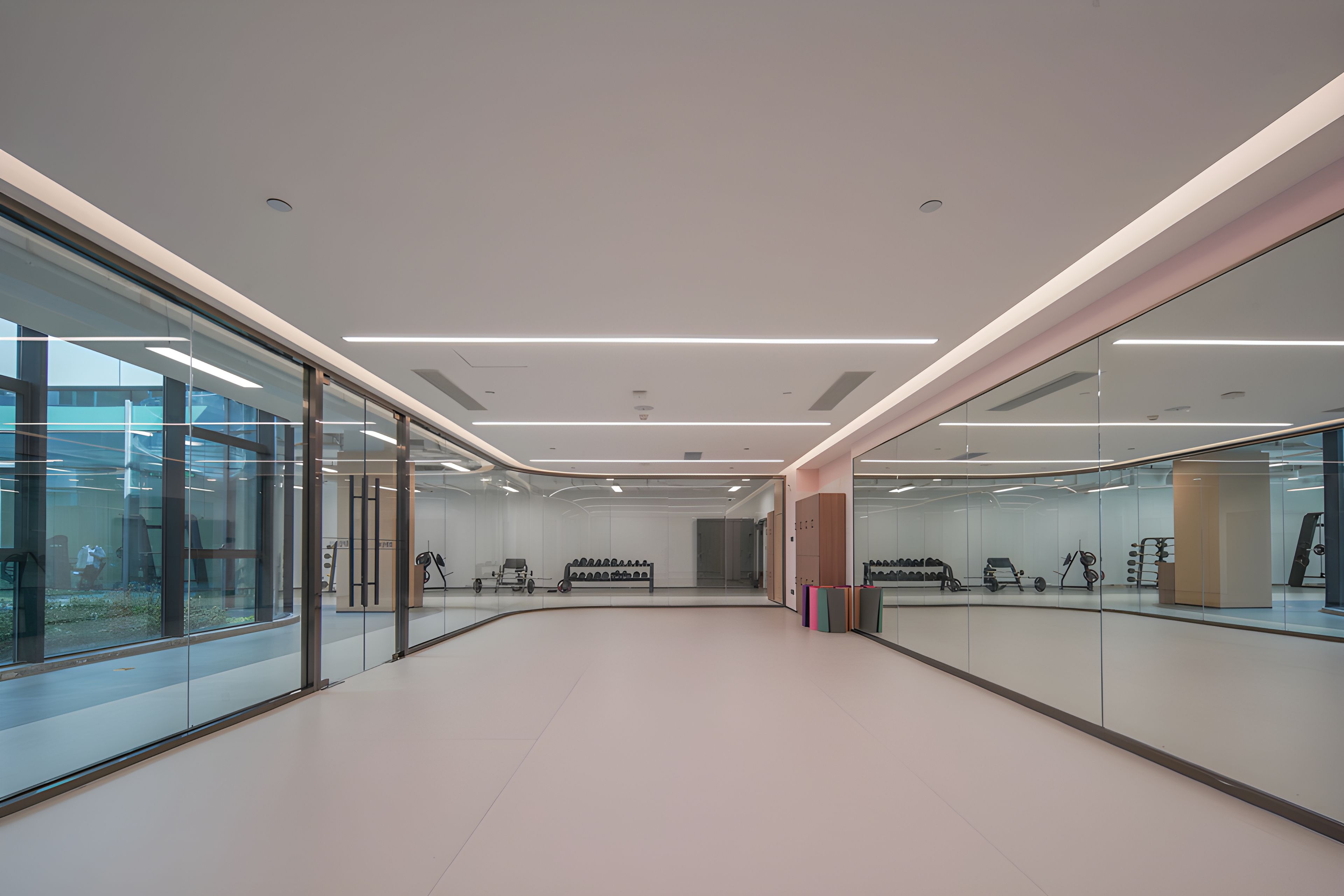 Un interior moderno con paredes de vidrio, un pasillo central y equipo de ejercicio.