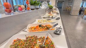A buffet line with various dishes, including salads, vegetables, and meats.