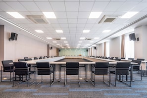 A conference room with a long table, chairs, and a projector screen.