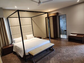 A four-poster bed with a herringbone floor pattern, a bedside table, and a bench. - Charming 2-bedroom country house villa in lovely Indore with AC (Indore)