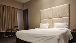 Una camera d'albergo con un letto grande, una sedia, un armadio e una porta.