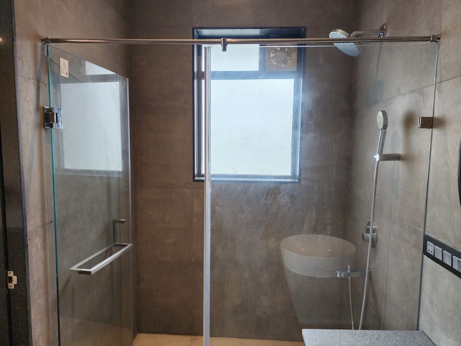 Un baño moderno con ducha vidriada, ventana, lavamanos y ducha.