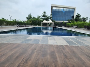 A swimming pool with a modern building in the background. - Charming 2-bedroom country house villa in lovely Indore with AC (Indore)