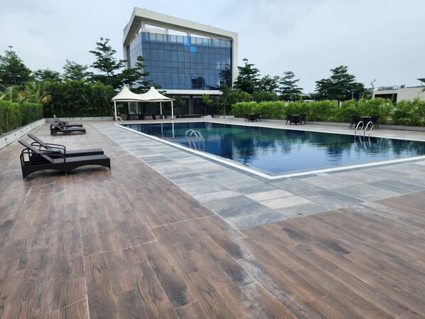 A swimming pool with lounge chairs and a modern building in the background.
