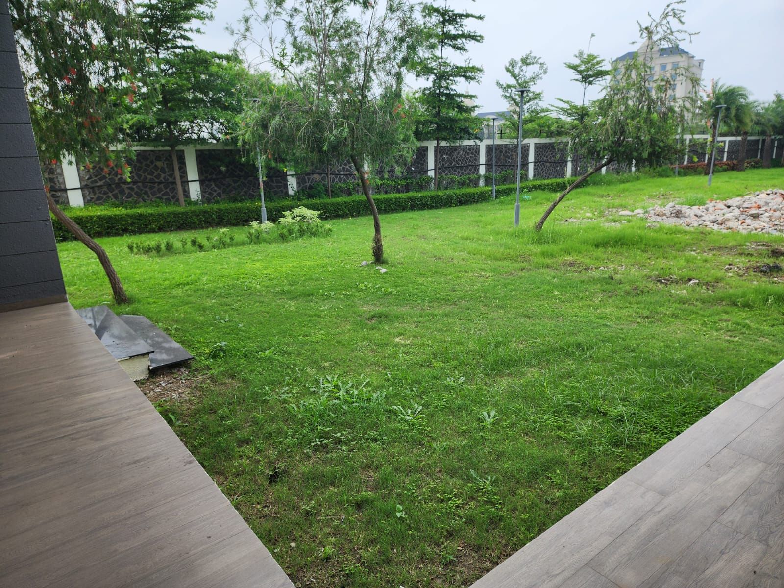 Un área verde bien cuidada con árboles y un muro de piedra al fondo.
