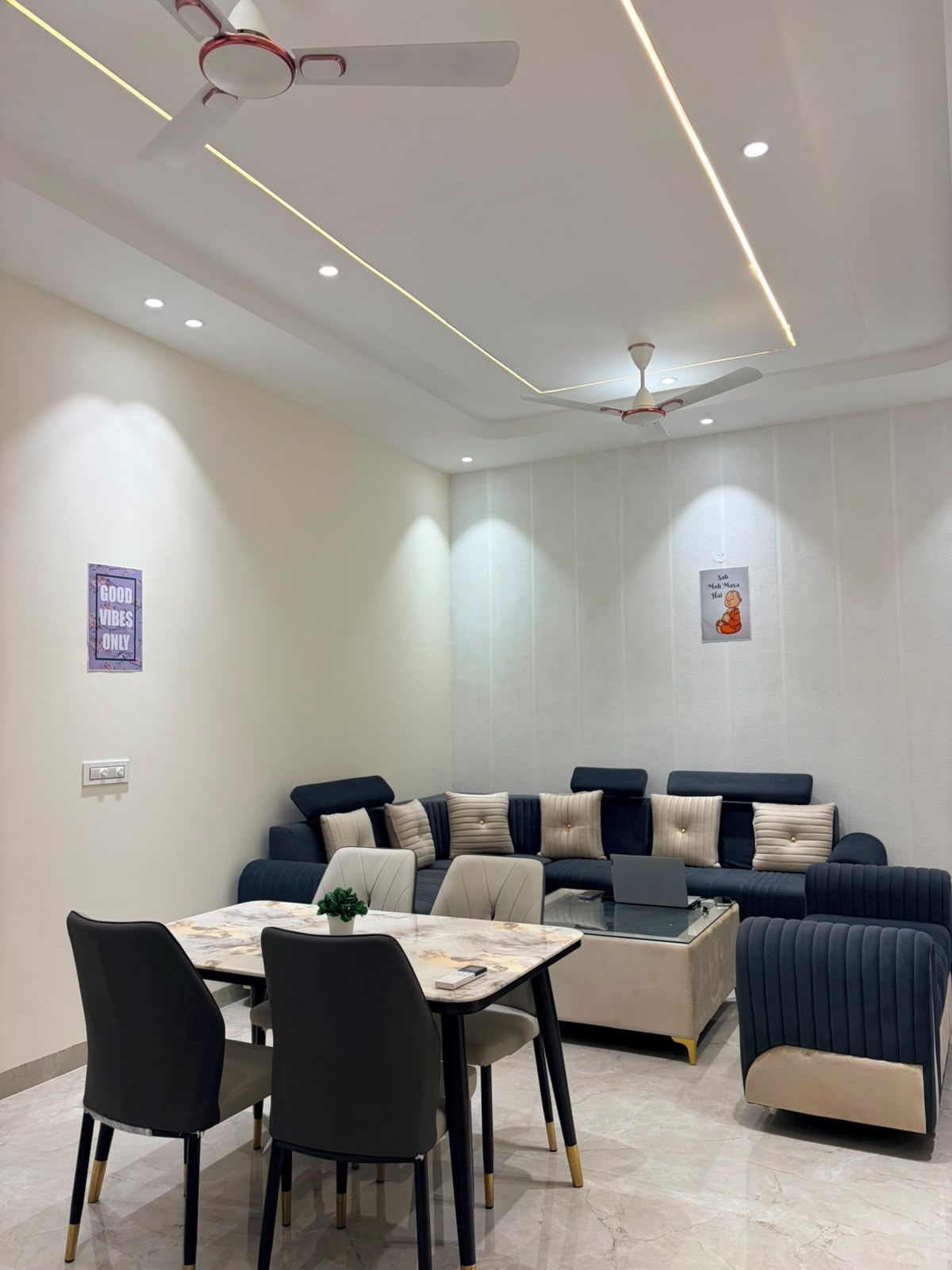 Ein modernes Wohnzimmer mit einer Sofagarnitur, einem Esstisch mit Stühlen und Deckenventilatoren.