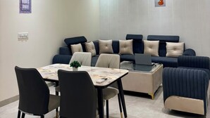 Un salon moderne comprenant un ensemble de canapés, une table à manger avec des chaises et des ventilateurs de plafond.