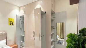Une chambre à coucher avec un lit, une armoire, un miroir et une plante en pot.