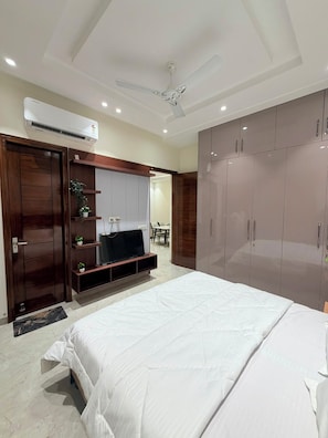 Ein Schlafzimmer mit Bett, Kleiderschrank, Fernseher und Deckenventilator.