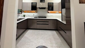 Une cuisine moderne dotée d’un îlot central, d’appareils électroménagers intégrés et d’un luminaire encastré au plafond.