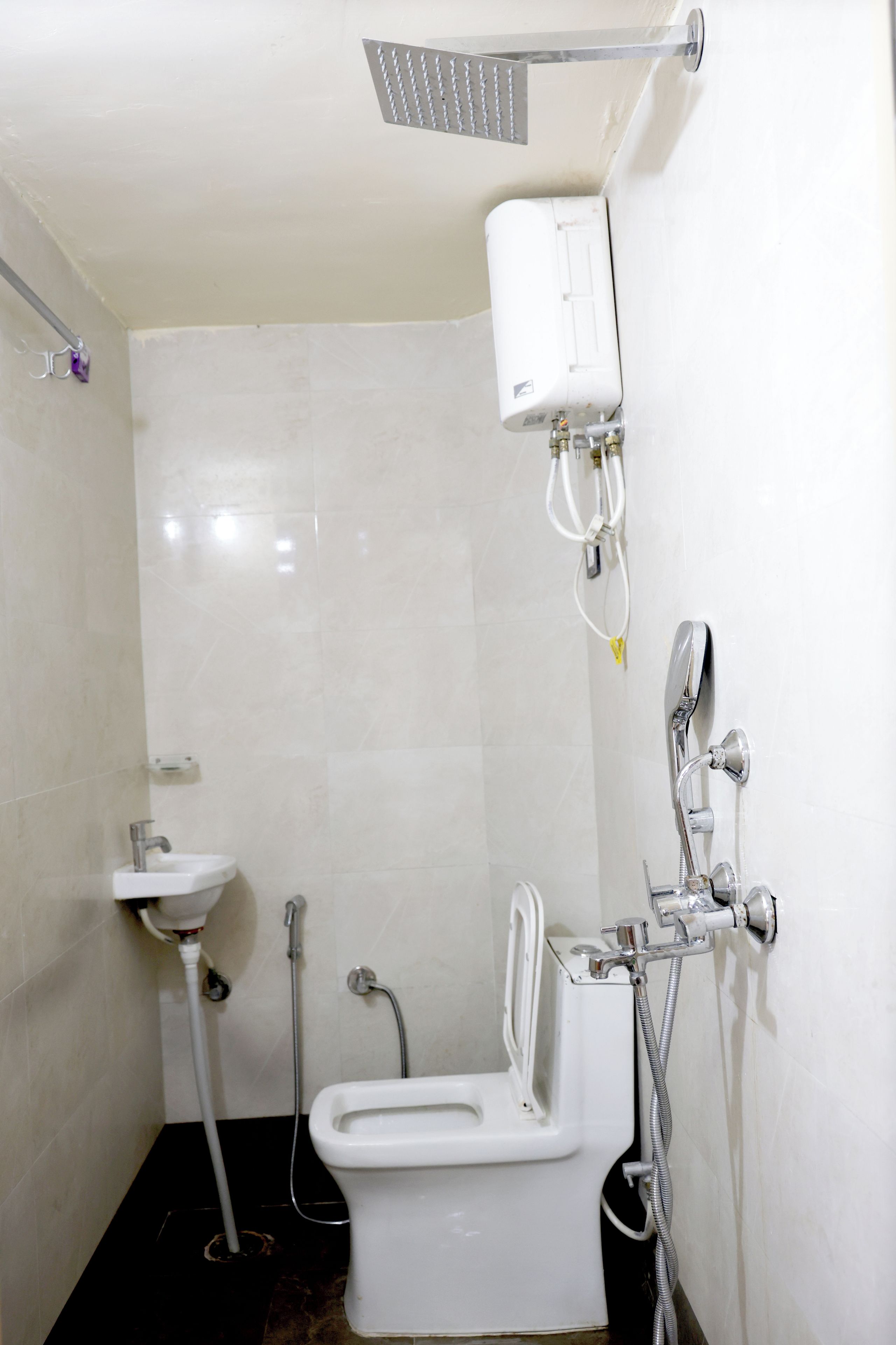 Een badkamer met toilet, wastafel, douche en handdoekrek.