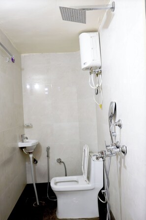 A bathroom with a toilet, a sink, a shower unit, and a towel rack. - Maruti Hotel  (Jodhpur)