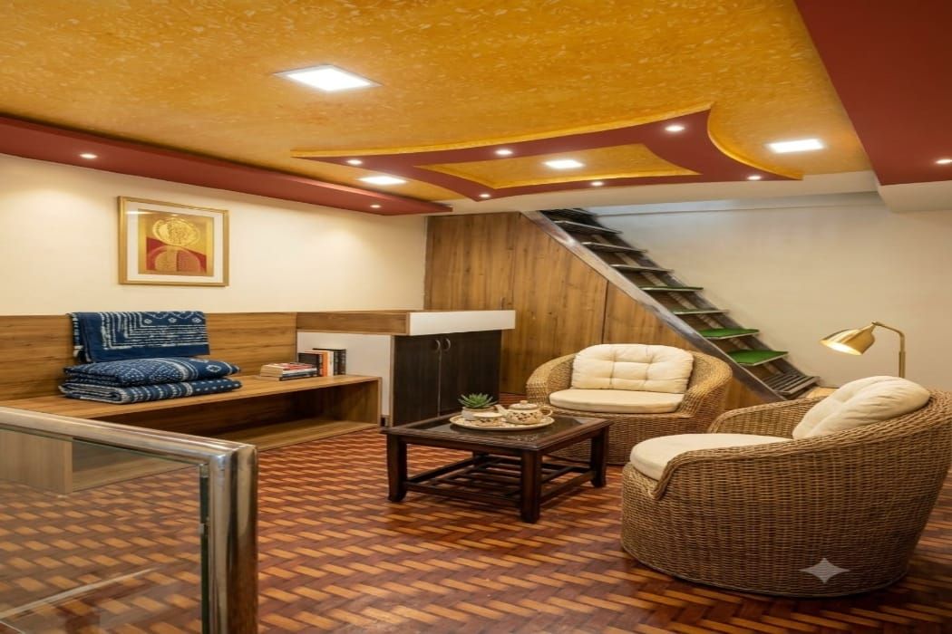Una sala de estar acogedora con un sofá, dos sillones, una mesa de centro y una escalera que sube a un nivel superior.