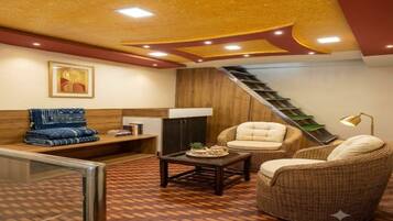 Una sala de estar acogedora con un sofá, dos sillones, una mesa de centro y una escalera que sube a un nivel superior.