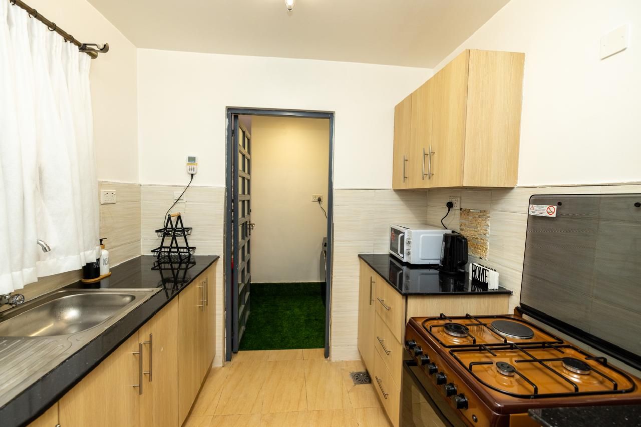 A compact kitchen with a gas stove, a microwave, and wooden cabinets.