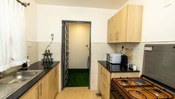 A compact kitchen with a gas stove, a microwave, and wooden cabinets.