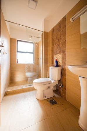 A bathroom with a toilet, a shower, and a sink. - Elite suites near all embassies (ruaka cytonn)