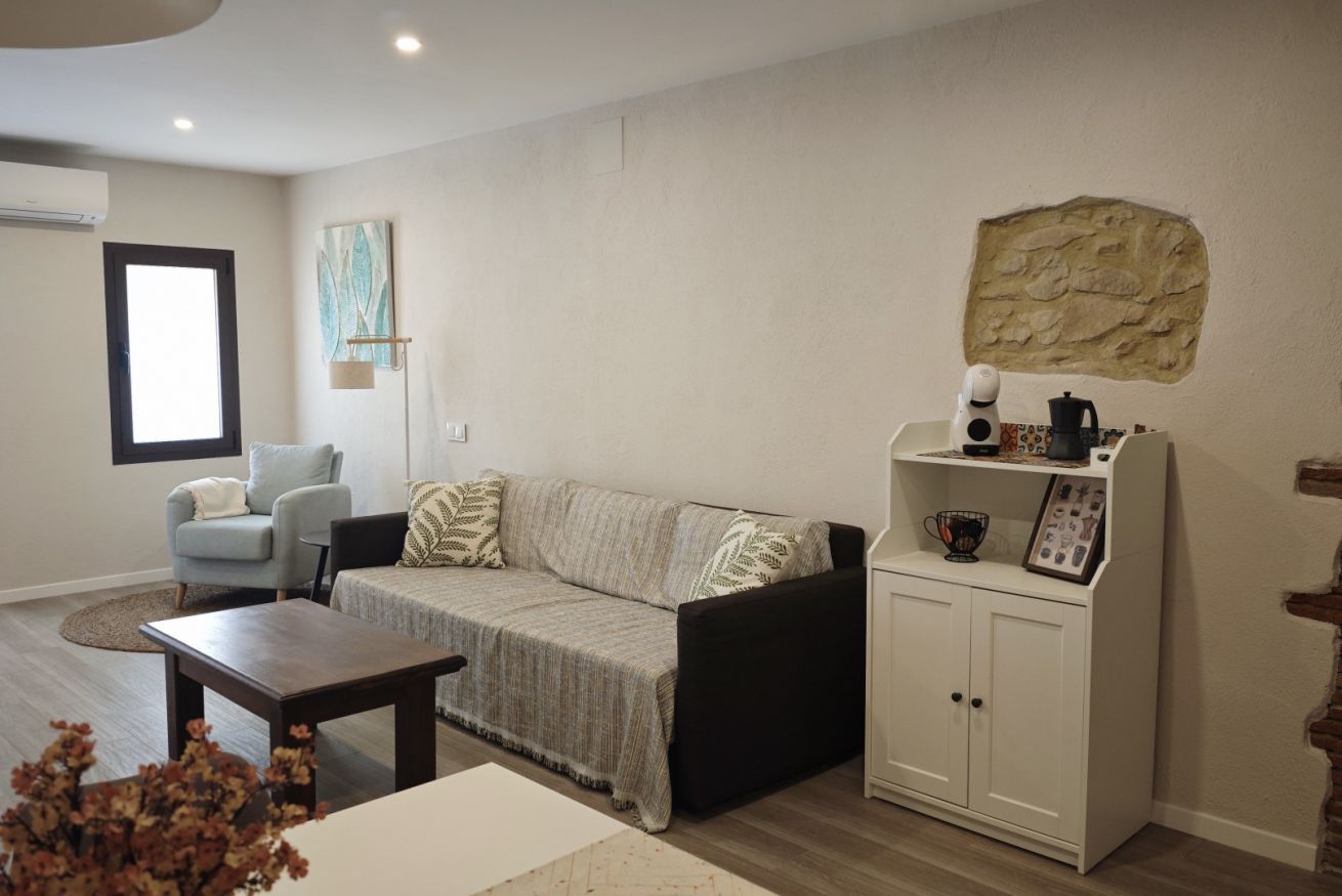 A living room with a sofa, armchair, coffee table, and a cabinet with a stone accent wall.