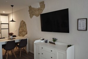 A modern kitchen with a built-in refrigerator, a dining area with a white table and black chairs, and a flat-screen TV mounted on the wall. - Can Costals Lavanda In Pals (Masos de Pals)