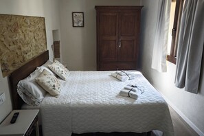 A hotel room with a bed, a wardrobe, a nightstand, a remote control, and a window with curtains. - Can Costals Lavanda In Pals (Masos de Pals)
