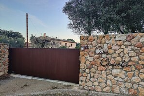 A gated entrance with a stone wall and a metal gate. - Can Costals Lavanda In Pals (Masos de Pals)