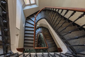A spiral staircase with a metal railing and a wooden handrail, leading to an upper floor. - Finestra sulle Porte Palatine by Wonderful Italy (Torino)