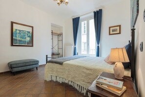 A bedroom with a bed, a bench, a lamp, and a bookshelf. - Finestra sulle Porte Palatine by Wonderful Italy (Torino)