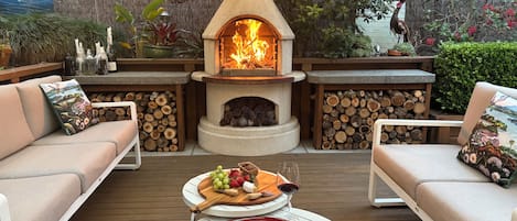 An outdoor patio with a stone fireplace, seating area, and a table with a decorative plate.